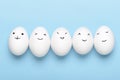 Kawaii faces on white eggs on a blue background. Cartoons, decoration food for children. Top view, flat lay. Royalty Free Stock Photo