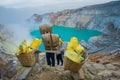 KAWEH IJEN, INDONESIA: Local miners carrying heavy baskets of yellow sulfur rocks up mountain side, tourist hiking