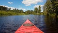 Kayak on a calm wide river surrounded by untouched bright green mixed forest