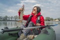 Kayak fishing. Fisher girl holding pike fish trophy on inflatable boat with fishing tackle at lake Royalty Free Stock Photo