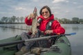 Kayak fishing. Fisher girl holding pike fish trophy on inflatable boat with fishing tackle at lake Royalty Free Stock Photo