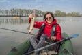 Kayak fishing. Fisher girl holding pike fish trophy on inflatable boat with fishing tackle at lake Royalty Free Stock Photo