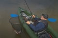 Kayak fishing at lake. Fisherman caught pike fish on inflatable boat with fishing tackle Royalty Free Stock Photo