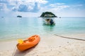 Kayak orange boat with speed boat anchor on white sand Royalty Free Stock Photo