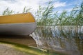 Kayak is parked by the rocky shore of the lake, against the backdrop of green grass and sky. Lifestyle. Royalty Free Stock Photo