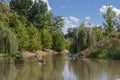 Kayaker paddles past canoe filled with plants on river in Gathering Place public park with paddle boaters and