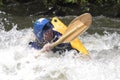 Kayaker partially submerged in a river rapid