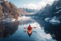 kayaker is sailing on red kayak on blue river on winter trip with a landscape with snowy mountains and forest Royalty Free Stock Photo