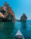 Kayaking along the coast of the island near the rocks. Canoeing adventure on a calm sea with blue water Royalty Free Stock Photo