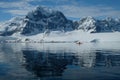 Antarctica orange kayak in a mirror blue bay beneath snow capped mountains