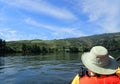 Kayaking in kayak on river with hills and plants and orange vest