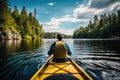 Kayaking on the lake in the mountains. A man in a yellow kayak sails along the shore, A person\'s rear view enjoying an eco-