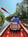 Kayaking A teenage boy in a life jacket is canoeing down the river. Trees grow along the banks. Rear view. Sports tourism and Royalty Free Stock Photo