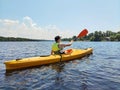 Kayaking A young boy is sailing a canoe on a wide river. Rear view. Sports tourism and active leisure in beautiful summer nature Royalty Free Stock Photo