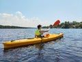 Kayaking A young boy is sailing a canoe on a wide river. Rear view. Sports tourism and active leisure in beautiful summer nature