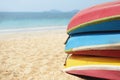 Kayaks stacked on sand beach. Colorful boats in front of sea coast.