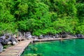 Kayangan Lake - Blue crystal water in paradise lagoon - walkway on wooden pier in tropical scenery - Coron island, Palawan, Royalty Free Stock Photo