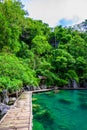 Kayangan Lake - Blue crystal water in paradise lagoon - walkway on wooden pier in tropical scenery - Coron island, Palawan, Royalty Free Stock Photo