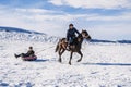 Kazakh boys ride horses and tubing in winter in steppe in Kazakhstan. Shymkent, Kazakhstan - January 27, 2024