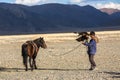 Kazakh Eagle Hunter Berkutchi with horse while hunting to the hare with a golden eagles on his arms Royalty Free Stock Photo