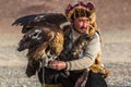 Kazakh Eagle Hunter Berkutchi with horse while hunting to the hare with a golden eagles on his arms Royalty Free Stock Photo