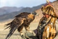 Kazakh Eagle Hunter Berkutchi with horse while hunting to the hare with a golden eagles on his arms Royalty Free Stock Photo