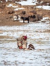 Kazakh eagle hunter in traditional clothing, with a golden eagle on during annual national competition with birds of prey