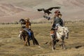 Kazakh Eagle Hunters traditional clothing, while hunting to the hare holding a golden eagles on his arms in desert mountain