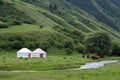 Kazakh traditional yurt in green mountains with grazing horses near and river. Nature, landscape house Royalty Free Stock Photo