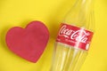 Kazakhstan, Kostanay, February 3, 2023, empty glass bottle Coca Cola classic and red heart yellow background.
