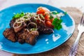 Kazan kebab with vegetables on a blue plate side view