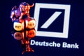 Metal bull stands on buy-sell dices on background of Deutsche bank logo