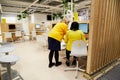 Kazan, Russia - December 22, 2019: The seller in the brand yellow clothes in the trading room IKEA. Interior of large IKEA store