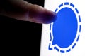 The finger reaches for the Signal encrypted instant messaging service logo on the smartphone screen