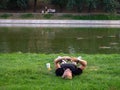 Kazan, Russia. 20.08.2021 A man is lying on the lawn near the lake with a phone