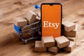 Smartphone with Etsy logo on the screen, shopping cart and parcels Royalty Free Stock Photo