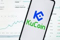 A smartphone with the KuCoin logo on the background of the live trading webpage. KuCoin dashboard