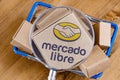 Modified photo of Mercado Libre logo on a box under magnifying glass in the shopping cart