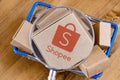 Modified photo of Shopee logo on a box under magnifying glass in the shopping cart