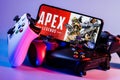 A smartphone with the frame from Apex Legends on the screen surrounded by gamepads Royalty Free Stock Photo