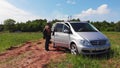 Geodesist with colleague stands near grey van on oil field