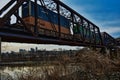 KC Skyline under Intermodal railroad infrastructure bridges over the Kansas River from Kaw Point Park with a passing Freight Train