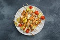 Kebab chicken, zucchini and tomatoes on skewers in a plate. Dark table Copy space