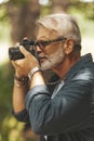 A keen elderly man with a beard takes pictures. Active leisure and hobby that inspires