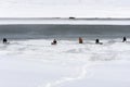 Keen fisherman catches fish in the winter in the hole made in the ice covering the river bed. Next to the fisherman melt the ice a