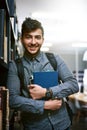 Keen to get that college degree. Portrait of a happy young man carrying books in a library at college. Royalty Free Stock Photo