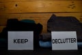 Keep and Declutter write on a sticky note between fashion clothes folded and stack on wooden background