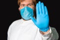 Keep distance concept doctor stop hand sign in face mask on black background, global pandemic corona virus conditions time