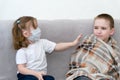 Keep a distance with sick people. A boy and a girl in a mask sit on a sofa in the distance and the girl pushes away the sick boy Royalty Free Stock Photo