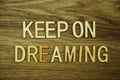 Keep On Dreaming text message on wooden background